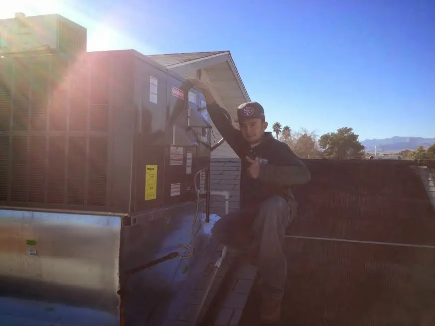 HVAC technician performing AC Tune-Up on a rooftop unit in Saline