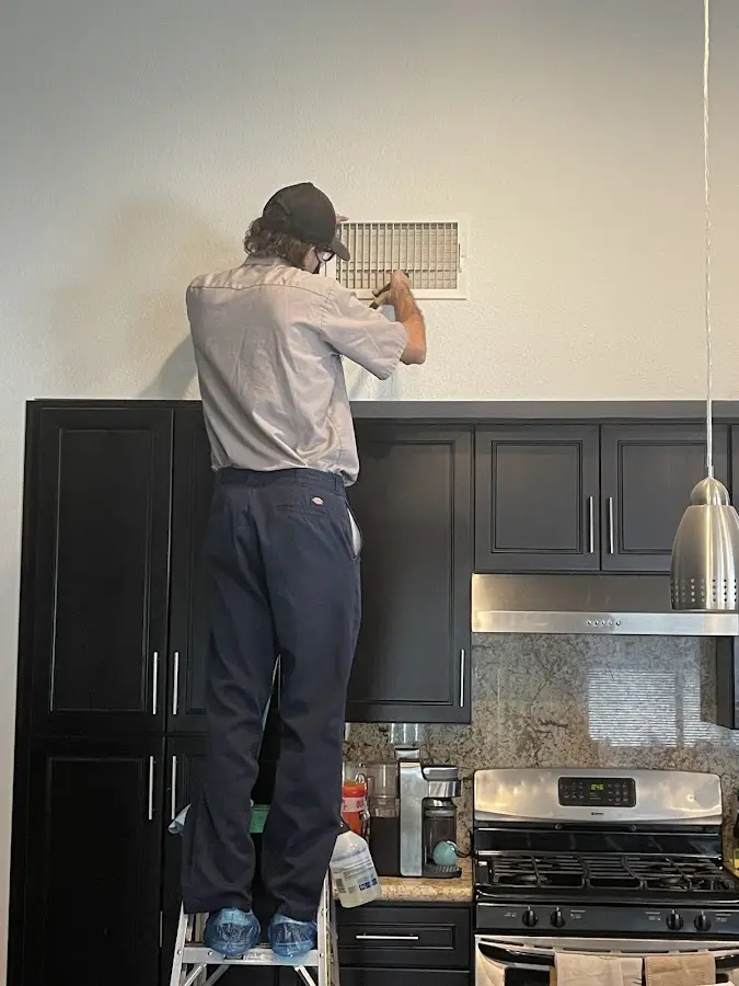 Technician inspecting an air vent during HVAC service in Saline